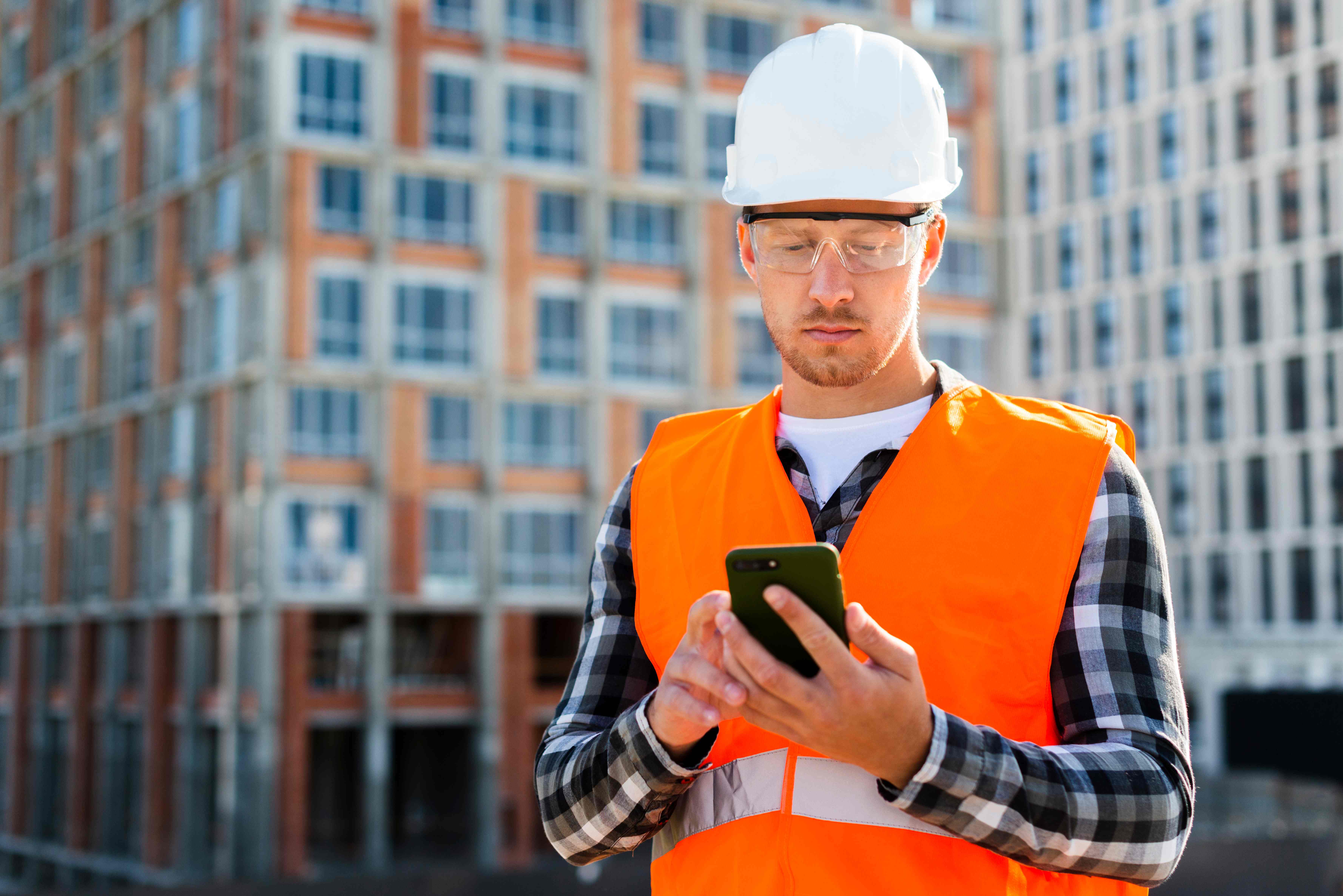 Construction engineer using mobile app on smartphone at building site